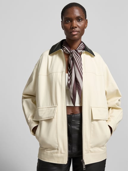 Frauenmodel trägt Relaxed Fit Jacke mit Umlegekragen von Anine Bing aus Reiner Baumwolle, AufgesetzteTaschen, Reißverschluss, cremefarbener Stoff, Rückenlänge 70 cm, Brustweite 59 cm, Ärmellänge 55 cm, Ganzkörperansicht von vorne.
