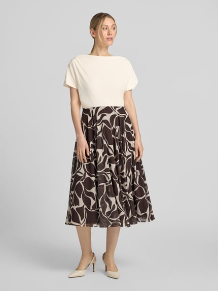 Frauenmodel trägt Cocktailkleid im 2-in-1-Look mit Drapierungen von Christian Berg Cocktail, A-Linie, Midikleid, abstraktes Muster, Farben Creme und Dunkelbraun, Rückenlänge bei Größe 36: 116 cm, Brustweite bei Größe 36: 45 cm, Ganzkörperansicht von vorne.