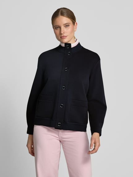 Frauenmodel trägt Sweatjacke mit Stehkragen und Knopfleiste von Marc Cain aus Baumwoll-Mix mit Stretch-Anteil, Regular Fit, Eingrifftaschen, dunkelblau, kombiniert mit hellrosa Hose, glatte Textur, Ganzkörperansicht von vorne.