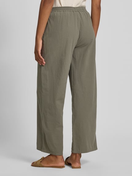Frauenmodel trägt Stoffhose in verkürzter Passform Modell 'CISSIE' von Soyaconcept aus Reine Baumwolle, Wide-Leg-Pants, elastischer Bund mit Tunnelzug, Bundweite für Größe S 37 cm, Innenbeinlänge 73 cm, olivegrüne Farbe, strukturierte Oberfläche, Ganzkörperansicht Rückansicht.
