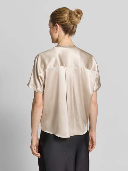 Vrouwenmodel draagt Relaxed Fit Seidenbluse mit Rundhalsausschnitt van HERZENS in beige zijde-mix met knoopsluiting, korte mouwen, ruglengte 63 cm, mouwlengte 18 cm, gladde textuur, gehele rugaanzicht.