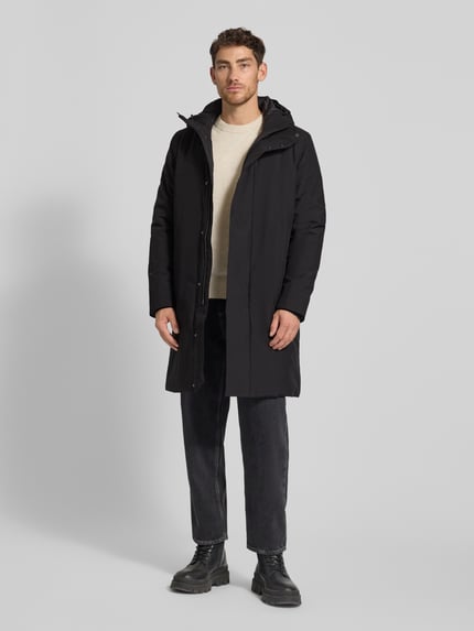 Männermodel trägt schwarzen Parka mit Kapuze Modell 'BARRY' von SAVE THE DUCK, verdeckter Reißverschluss, Ganzkörperansicht von vorne.
