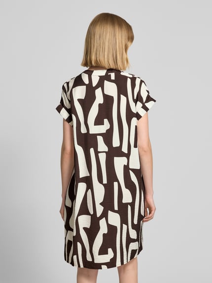 Vrouwenmodel draagt knielengte dames jurk van viscosemix, loose fit, tuniekkraag, model 'Wulana dune' van OPUS, ruglengte maat 36: 92 cm, borstwijdte 58 cm, mouwen met vaste omslag, zwart-witte abstracte print. Ganzkörperansicht Rückansicht.