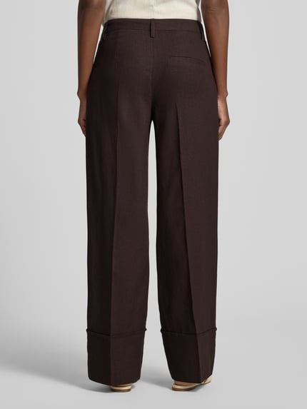 Frauenmodel trägt Hose aus Leinen-Viskose-Mix Modell 'Ottavie' von mbyM, dunkelbraun, Wide Leg, Bügelfalten, Ganzkörperansicht Rückansicht, Damen Hose, Bundweite 39 cm, Innenbeinlänge 81 cm bei Größe S.