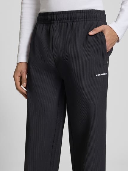 Männermodel trägt Sweatpants mit Strukturmuster und elastischem Bund von Pegador, Material-Mix mit Stretch-Anteil, Relaxed-Fit, Nahaufnahme Oberkörper.