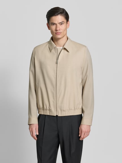 Männermodel draagt Regular Fit blouson uit scheerwolmix model 'HELLYS251X' van HUGO, look: effen, platte kraag, ritssluiting, lange mouw, elastische rompzoom en mouwboord, zij-steekzakken, binnenzak, kleur beige. Ganzkörperansicht van voren.