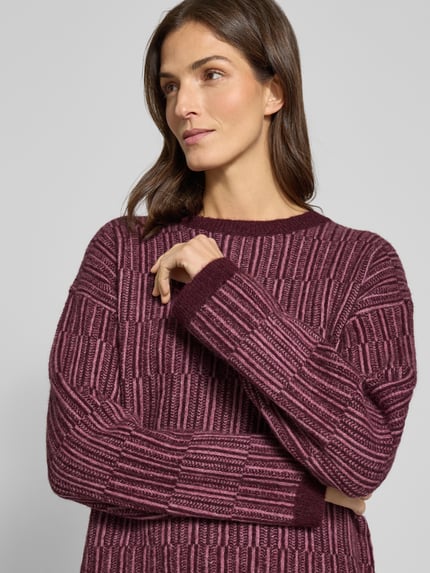 Vrouwenmodel draagt Relaxed Fit Pullover aus Woll-Mix mit Alpaka-Anteil Model 'FALVA' van Selected Femme, bordeaux all-over structuurpatroon, ronde hals, lange mouw, gebreide wolmix, detailopname bovenlichaam.