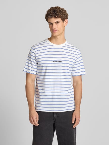 Männermodel trägt T-Shirt mit Streifenmuster und Label-Stitching von Jack & Jones, weiß-blau, Baumwolle, Relaxed Fit, Ganzkörperansicht von vorne.