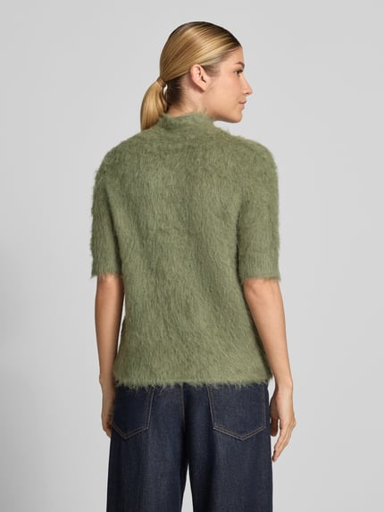Frauenmodel trägt Strickshirt aus Alpaka-Mix mit kurzem Stehkragen von someday, moosgrün, halbärmelig, Modell Tuomina, körpernaher Schnitt, Ganzkörperansicht Rückansicht.