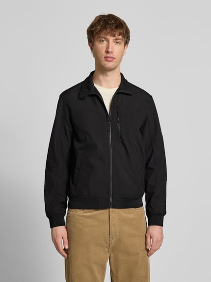 Männermodel trägt schwarze Regular Fit Bomberjacke mit Stehkragen Modell 'Parker' von Jack & Jones, Softshell, Ganzkörperansicht von vorne.