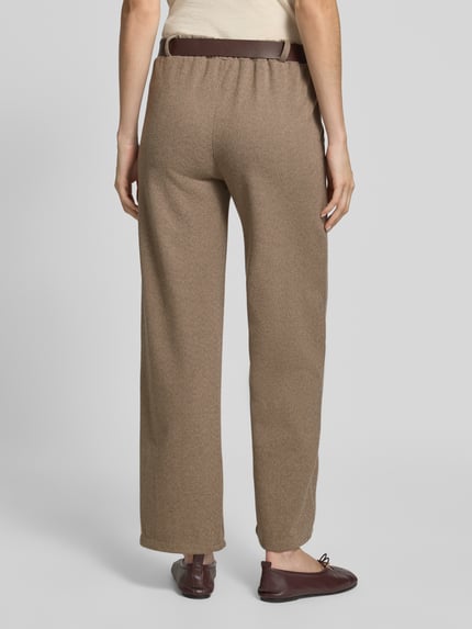 Frauenmodel trägt Regular Fit Weite Hose mit Bundfalten von ZABAIONE, braune Struktur, seitliche Eingrifftaschen, Ganzkörperansicht Rückansicht.