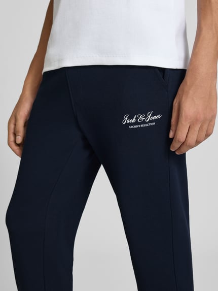 Männermodel trägt Sweatpants mit Label-Print Modell 'GORDON' von JACK & JONES, marineblau, seitliche Eingrifftaschen, Nahaufnahme Oberschenkel
