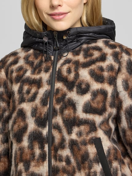 Frauenmodel trägt Mantel mit Kapuze von GIL BRET mit Allover Animal Print, glänzende Optik, Reißverschlüssen und Zugband, Nahaufnahme Oberkörper.