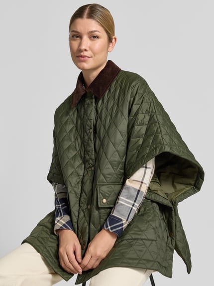 Frauenmodel trägt Oversized Poncho mit Umlegekragen Modell 'MILDRED QUILTED CAPE' von Barbour in Olivgrün mit Rautensteppung, Damen Poncho von Barbour, Nahaufnahme Oberkörper.