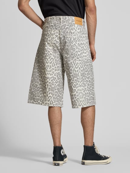 Männermodel trägt Shorts im Allover-Look Modell 'OWEN' von Jack & Jones in Grau mit Leo-Muster aus reiner Baumwolle, Relaxed-Fit, Eingrifftaschen, Bundweite bei Größe M 44 cm, Innenbeinlänge 37 cm, Ganzkörperansicht Rückansicht.
