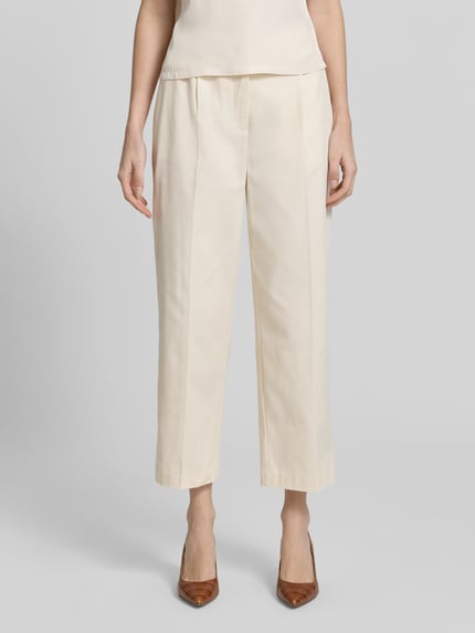 Frauenmodel trägt Cropped Hose mit Bügelfalten Modell 'Cisan Flow' von Someday in Creme, Baumwoll-Elasthan-Mix, Ganzkörperansicht von vorne.