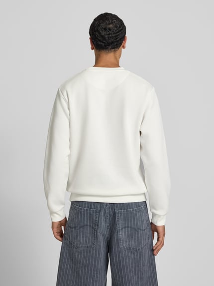 Männermodel trägt Sweatshirt mit Rundhalsausschnitt Modell 'BRADLEY' von JACK & JONES, weiß, Material-Mix, Gerippte-Abschlüsse, Lockerer-Schnitt, Rückenlänge 69 cm bei Größe M, Ärmellänge 68 cm bei Größe M, Ganzkörperansicht Rückansicht.
