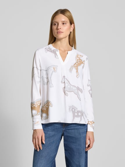 Vrouwenmodel draagt 'Tunikabluse mit V-Ausschnitt' van HERZENS in wit met allover paardendessin, regular fit, materiaalmix met stretch, voorkantaanzicht bovenlichaam.