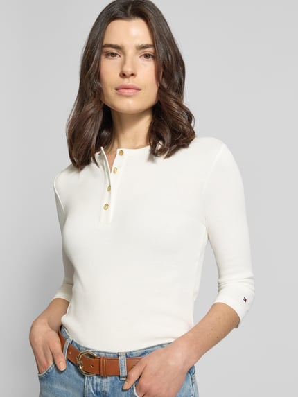 Frauenmodel trägt Slim Fit T-Shirt aus reiner Baumwolle von Tommy Hilfiger, Optik: unifarben, 3/4-Arm, Feinripp, Logo-Detail, Nahaufnahme Oberkörper.