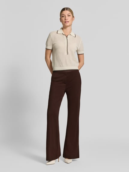 Frauenmodel trägt Flared Cut Hose aus Viskose-Mix mit Gesäßtaschen von Christian Berg Woman, braun, schlichte Textur, Ganzkörperansicht von vorne.