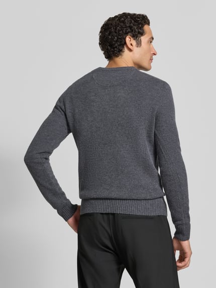 Männermodel trägt dunkelgrauen Slim Fit Strickpullover aus reiner Wolle mit Label-Stitching von MCNEAL, gerippte Abschlüsse, Ganzkörperansicht Rückansicht.