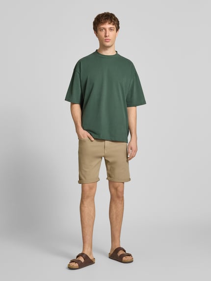 Männermodel trägt Jeansshorts mit Umschlag und Eingrifftaschen Modell 'RICK ALLEN' von Jack & Jones, beige, Regular Fit, Baumwoll-Elasthan-Mix, Ganzkörperansicht von vorne.