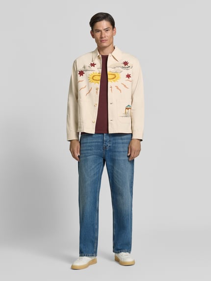 Männermodel trägt Regular Fit Overshirt mit Motiv-Prints- und -Applikationen von Scotch & Soda, beige, Jeans, Ganzkörperansicht von vorne