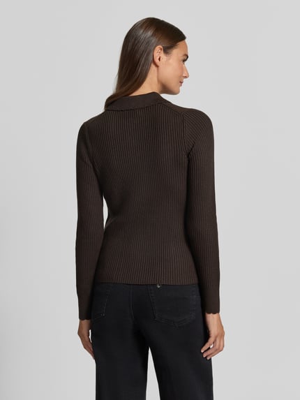 Frauenmodel trägt Cardigan aus Lanawolle mit Polokragen Modell 'ARHANYA' von DRYKORN, Ripp-Optik, schokobraun, Ganzkörperansicht Rückansicht.