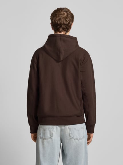 Männermodel trägt Hoodie mit Kapuze von Carhartt Work In Progress in Braun aus Baumwoll-Mix, Lockerer-Schnitt, Ganzkörperansicht Rückansicht.