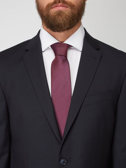 Männermodel trägt Krawatte aus reiner Seide von Monti, klassische Passform, dunkelrot, feine Struktur, Nahaufnahme Oberkörper.