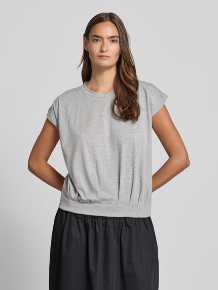 Frauenmodel trägt T-Shirt mit Rundhalsausschnitt und Kappärmeln von Christian Berg Woman im Material-Mix, Regular-Fit, Drapierungen, Rückenlänge 54 cm, Ganzkörperansicht von vorne.