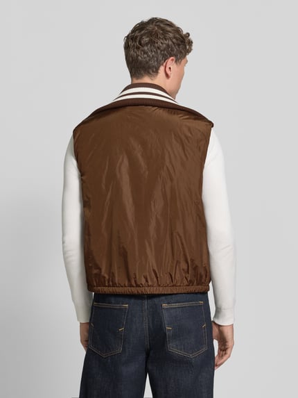 Männermodel trägt braune Weste mit Kontraststreifen von Dsquared2, elastischer Bund, Rippkragen, gerade Passform, Ganzkörperansicht Rückansicht.