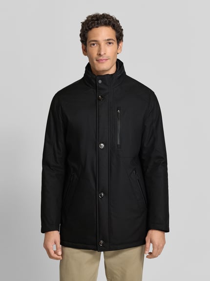 Männermodel trägt Jacke mit Stehkragen und Reißverschlusstaschen von bugatti in Schwarz, Regular Fit, glatte Oberfläche, Ganzkörperansicht von vorne. Rückenlänge 93 cm, Schulterbreite 43 cm, Brustweite 55 cm, Ärmellänge 64 cm.