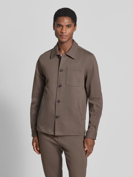 Männermodel trägt Slim Fit Hemdjacke mit Viskose-Anteil von Lindbergh in Braun, Umlegekragen, Knopfleiste, Brusttasche, Ganzkörperansicht von vorne.