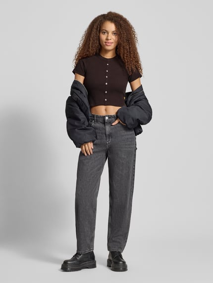 Kobiece modelka nosi czarne Cropped T-Shirt z guzikami model 'Heritage' od G-Star Raw, bawełna z elastanem, faktura prążkowana, widok całej sylwetki z przodu.