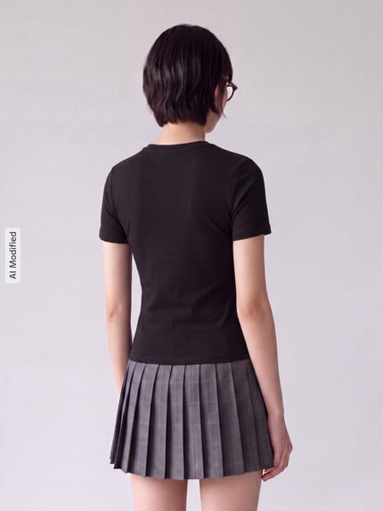 Frauenmodel trägt Slim Fit T-Shirt aus Baumwoll-Mix Modell 'RILEY' von ONLY, schwarz, kombiniert mit grauem Faltenrock, Ganzkörperansicht Rückansicht, Damen T-Shirt von ONLY, KI-modifiziertes Bild.