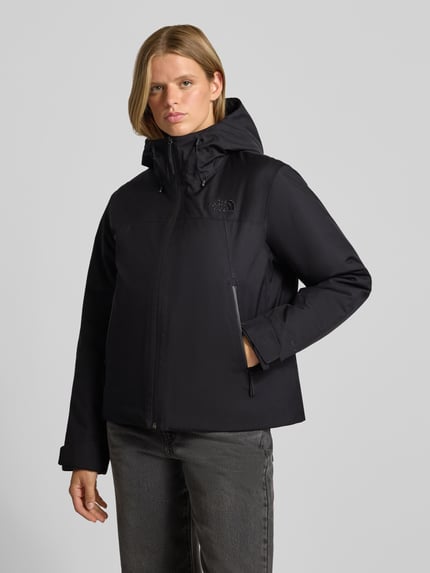 Frauenmodel trägt Jacke mit Logo-Stitching Modell 'RANGE DOWN' von The North Face in Schwarz, glatte Oberflächen, seitliche Eingrifftaschen, Ganzkörperansicht von vorne.