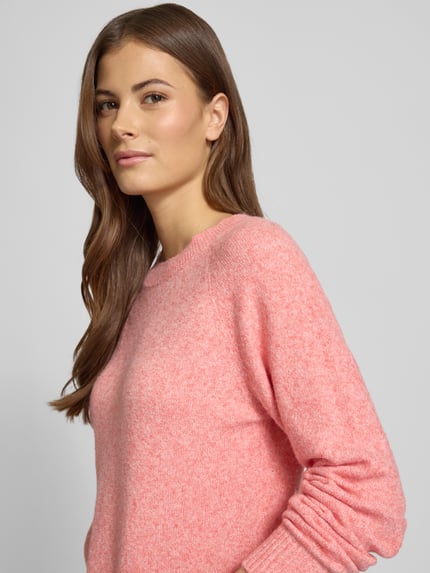 Vrouwenmodel draagt Regular Fit Strickpullover met Crew Neck model 'DOFFY' van Vero Moda, effen roze gebreid, detailopname bovenlichaam.