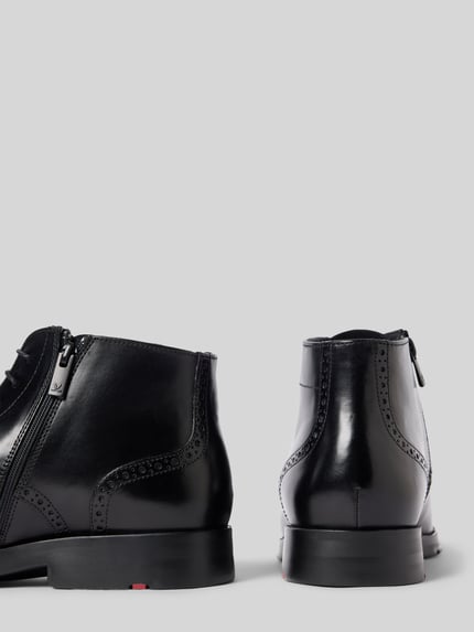 Produktfoto, Boots aus echtem Leder Modell 'EEZY' von LLOYD mit Schnürverschluss, Lochmuster und strukturierter Sohle, glänzend schwarzes Leder, abgerundete Form, Absatzhöhe 3 cm, Schafthöhe 11 cm, Schaftweite 11 cm, klassische Herrenschuhe vor grauem Hintergrund.