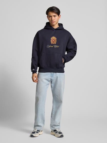 Männermodel trägt Hoodie mit Kapuze von PROHIBITED, Dunkelblau, Baumwoll-Mix, lockerer Schnitt, Label-Detail, Ganzkörperansicht von vorne.