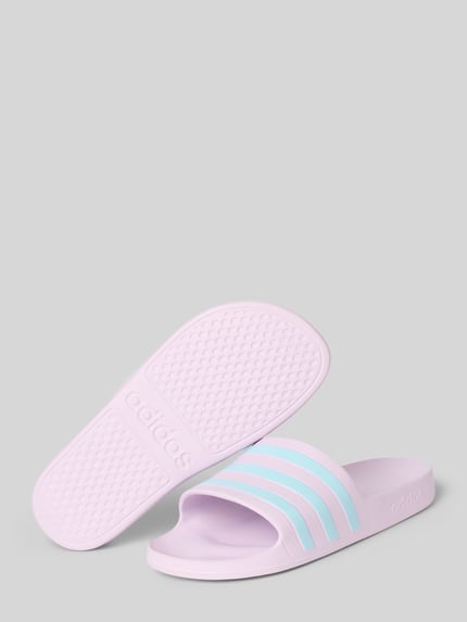 Produktfoto, Pantoletten mit Kontraststreifen von adidas Sportswear, fioletowy i błękitny, dwukolorowy wygląd, tworzywo sztuczne, płaska podeszwa, zaokrąglony nosek, gładka podeszwa, wsuwane, pasek z kontrastowymi paskami