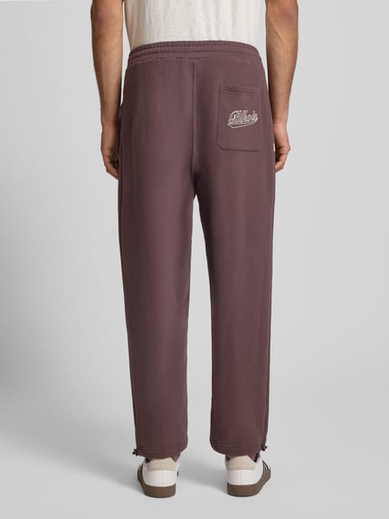 Männermodel trägt Regular Fit Sweatpants mit elastischem Bund Modell 'Source' von BLKVIS in Braun mit Gesäßtasche, Reine Baumwolle, 7/8-Länge, Ganzkörperansicht Rückansicht.
