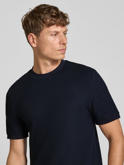 Männermodel trägt T-Shirt mit strukturierter Oberfläche Modell 'H-thompson 82' von BOSS, unifarben, Rundhals, Jersey, Nahaufnahme Oberkörper.