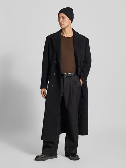 Męski model nosi T-Shirt mit Rollsaum od Filippa K z bawełny, prosty krój, okrągły dekolt, zrolowany brzeg, długość tyłu 70 cm w rozmiarze M, całkowity widok z przodu.