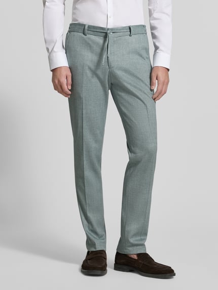 Männermodel trägt Straight Fit Stoffhose mit Bundfalten Modell 'Sparta' von Zuitable, Material-Mix mit Baumwoll-Anteil, hellgrün, Ganzkörperansicht von vorne.