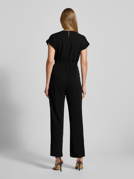 Frauenmodel trägt Jumpsuit mit Eingrifftaschen Modell 'Ko44a' von ZABAIONE, schwarzer Material-Mix mit Stretch-Anteil, Regular Fit, Ganzkörperansicht Rückansicht. Damen Jumpsuit, V-Ausschnitt, Rückenlänge bei Größe S 36 cm, Brustweite 41 cm, Ärmellänge 9 cm, Gesamtlänge 140 cm, Innenbeinlänge 70 cm.