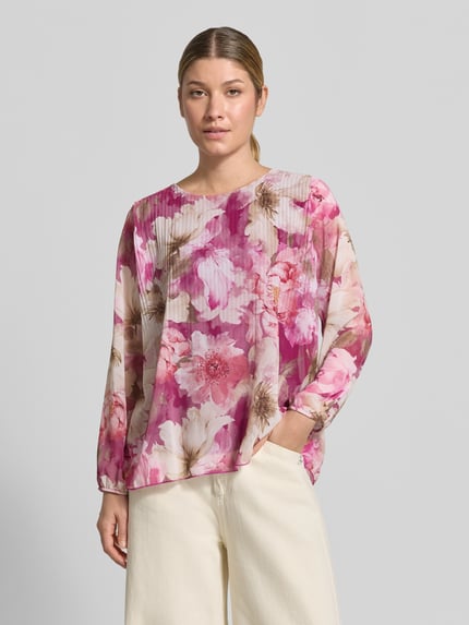 Modelka nosi bluzkę Regular Fit z plisami Model 'An44nii' od ZABAIONE, okrągły dekolt, wzór na całej powierzchni, długość tyłu 60 cm, długość rękawów 58 cm, jasnoróżowe i fioletowe odcienie, kwiatowy motyw, całość o lekko połyskującej teksturze, widok całej sylwetki z przodu.