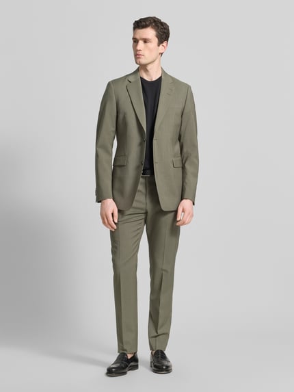 Männermodel trägt Straight Fit Stoffhose aus Reiner Wolle Modell 'Tentua' von Tiger Of Sweden in Olive, Gesäßtaschen, Ganzkörperansicht von vorne.