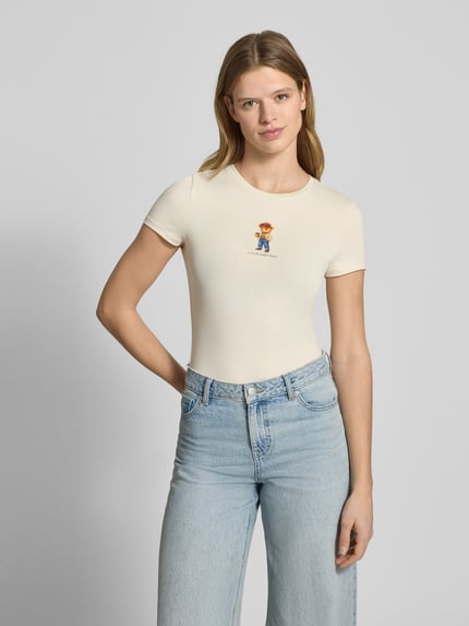 Frauenmodel trägt Slim Fit T-Shirt mit Logo-Print Modell 'Sweet' von Review in Beige, aus elastischem Baumwoll-Mix, Ganzkörperansicht von vorne.