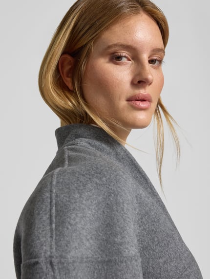 Frauenmodel trägt Kurze Wolljacke mit Stehkragen - curated by Viky Rader von Style Icon Collection in Hellgrau, weiche Textur, Detailaufnahme Oberkörper. Lockere Passform mit Stehkragen, Ziernähte, Überschnittene Schultern.